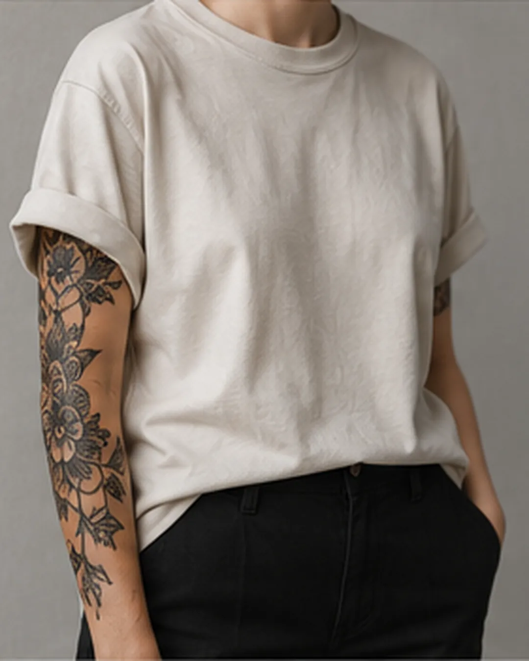 Person in weitem, hellem T-Shirt; der tätowierte Unterarm bleibt frei.